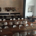 Wood tables with a bunch of white chairs.
