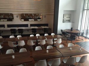 Wood tables with a bunch of white chairs.