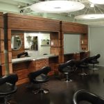 Wooden barbershop with large wooden cabinets and mirrors.